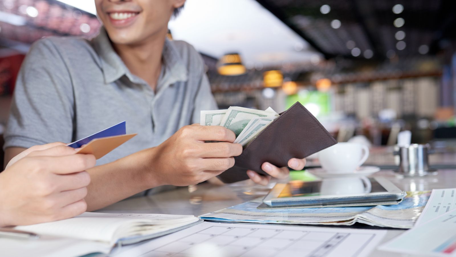A photo of Tourist counting cash at café table, public setting, natural light, realistic travel behavior.