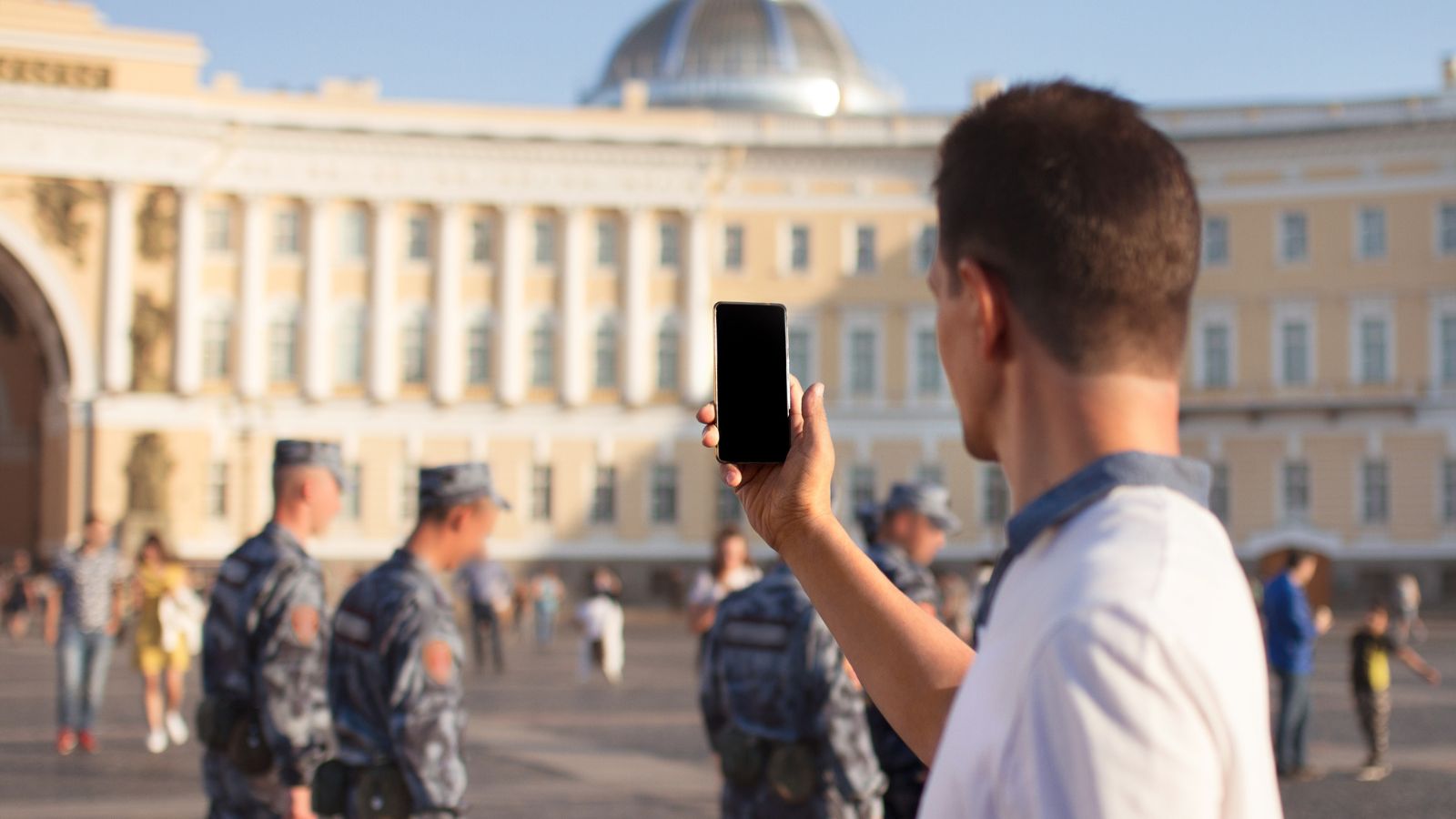 A photo of a Tourist taking a photo near a government building or public square.