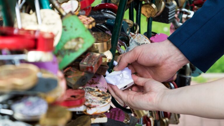 A photo of Couple attaching love lock to Paris bridge railing.