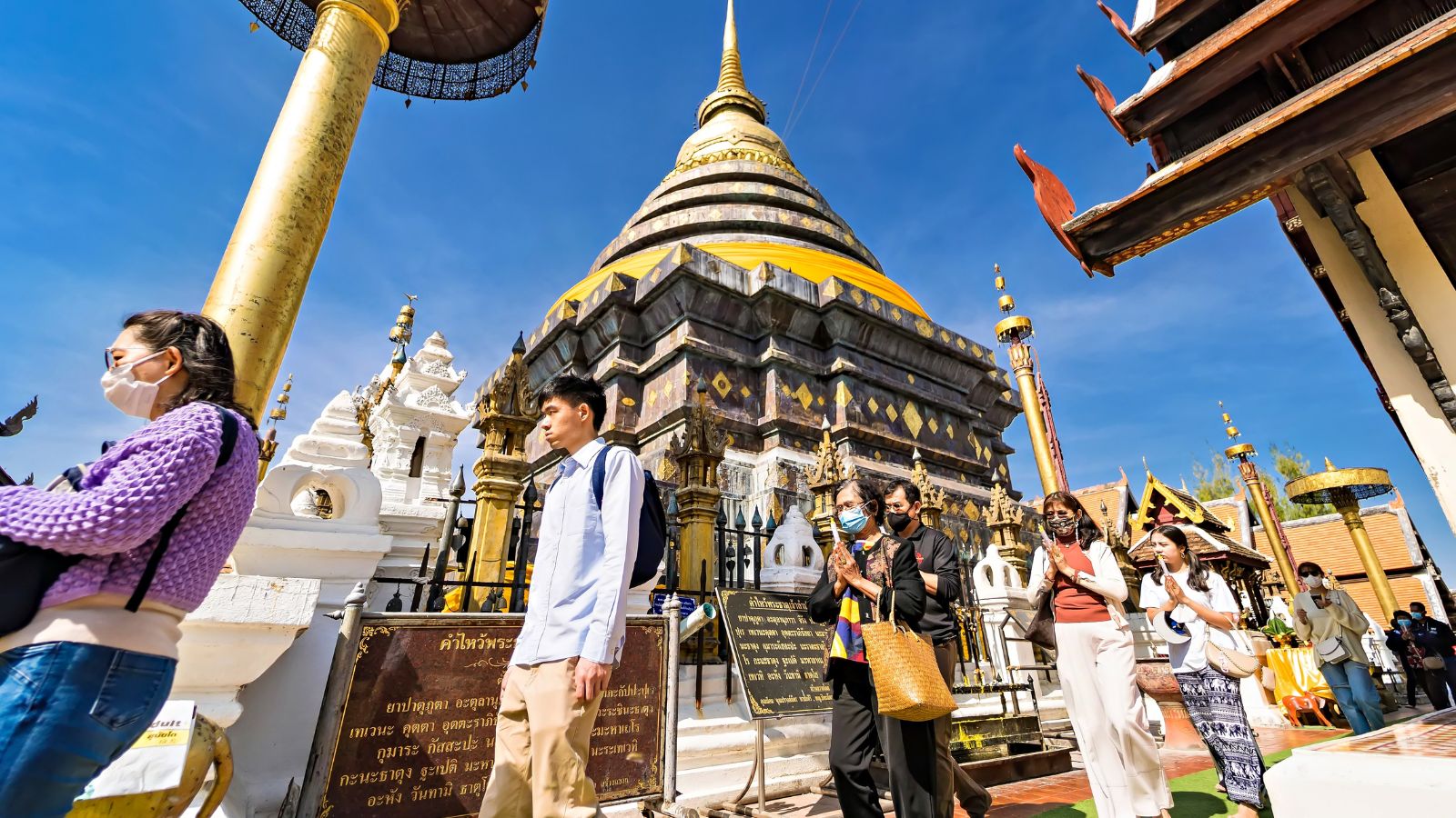 A photo of Tourists walking near a Buddhist temple in Thailand.