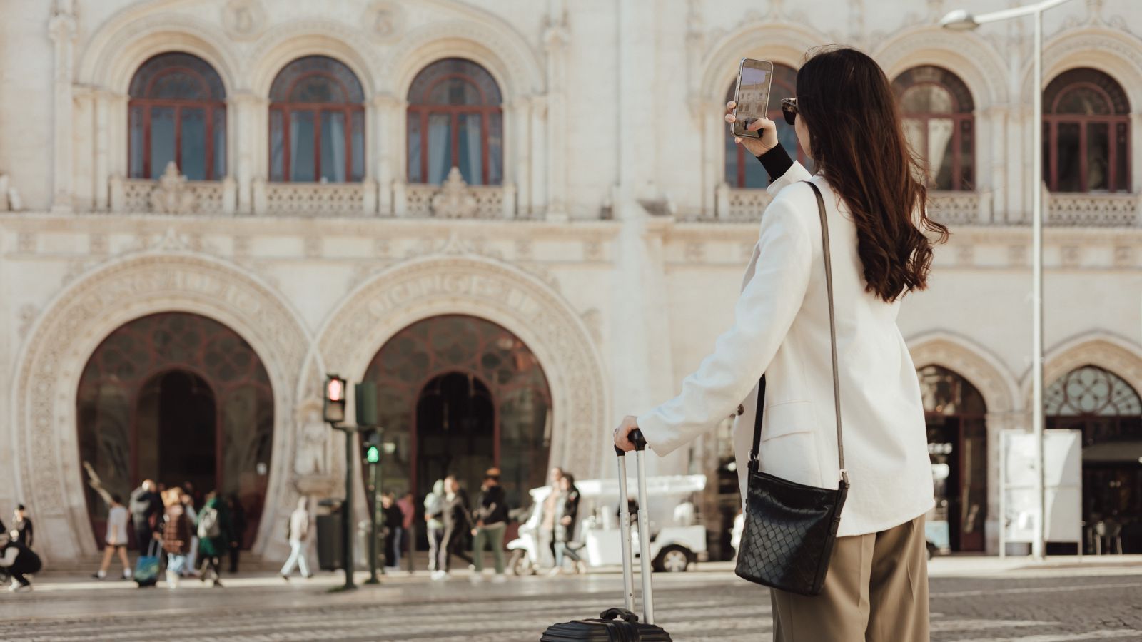 A photo of Traveler stepping aside near a wide plaza to check phone and take photos.
