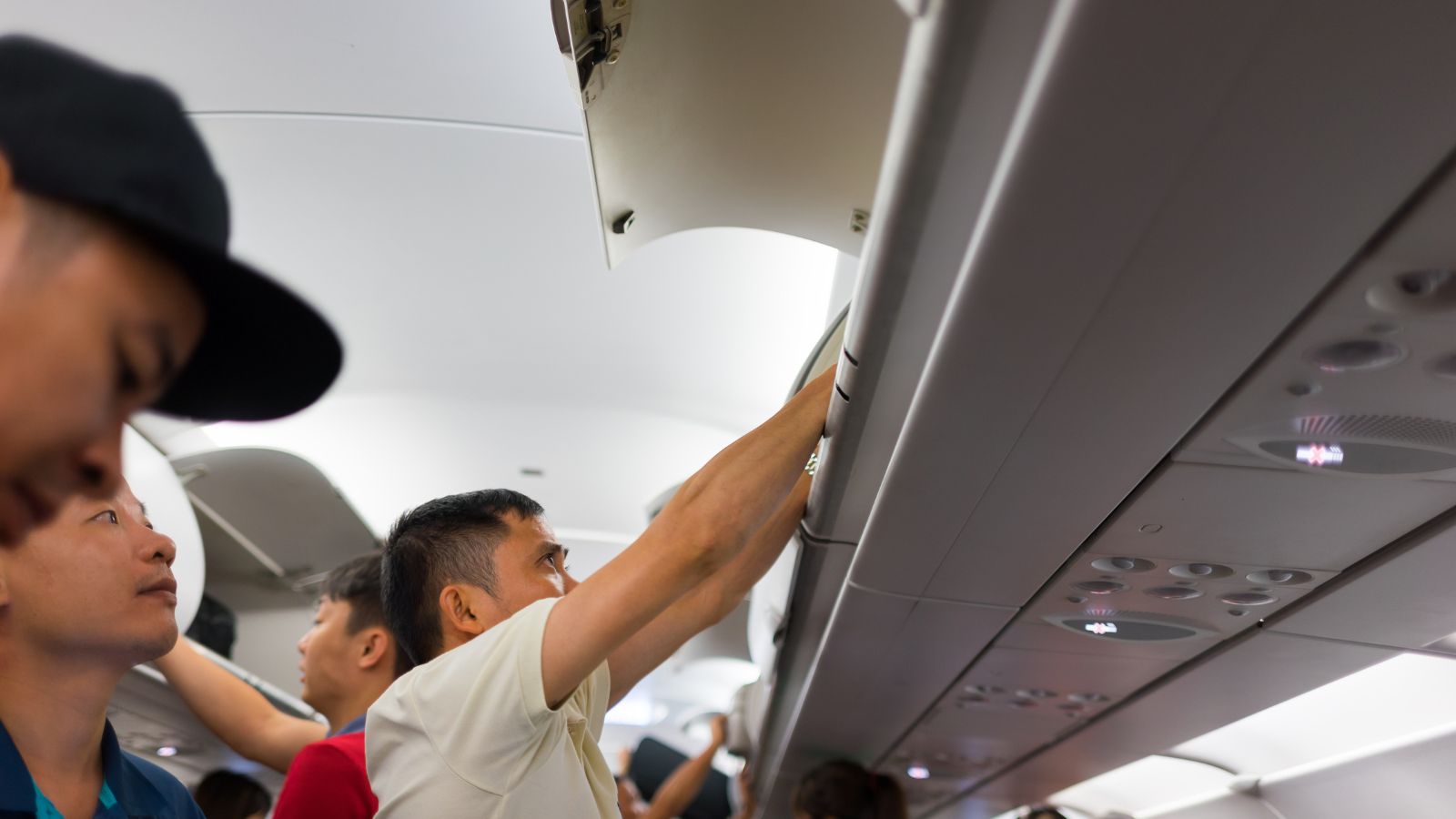 A photo of a man standing and arranging his bag on a bin.