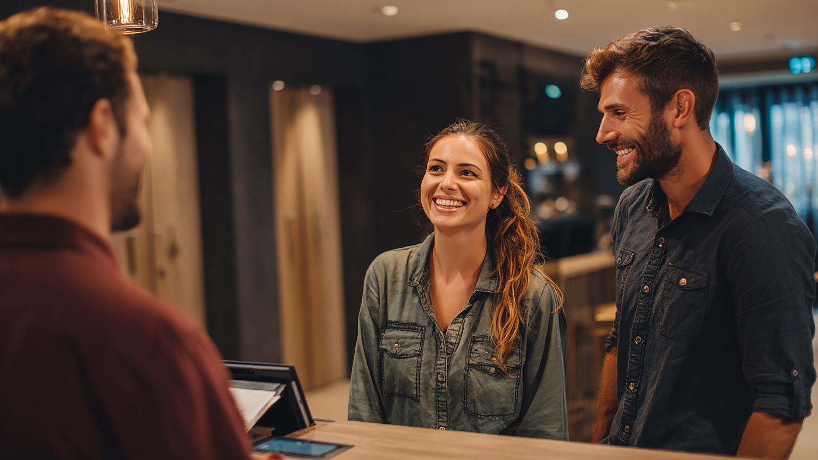 A picture that shows two couple happily facing the staff in hotel desk.