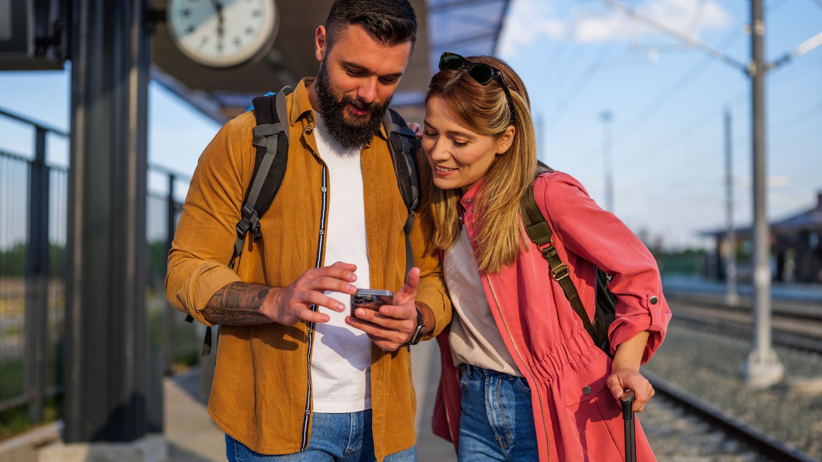 A photo of a couple looking at man's phone while the woman is holding the luggage.