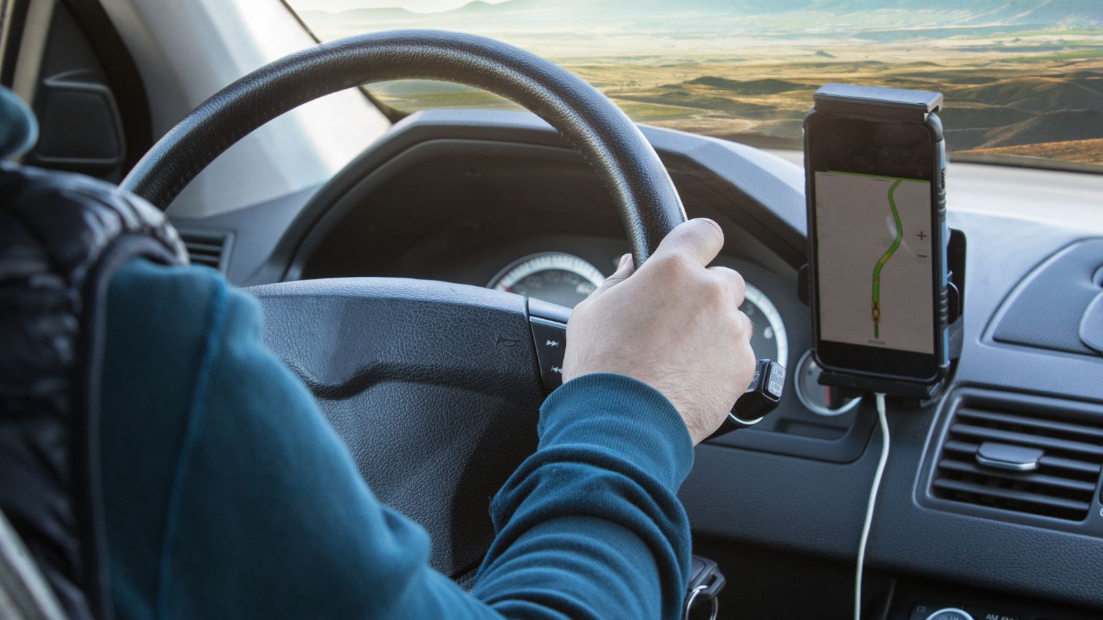 A photo of a Tourist checking Icelandic weather and road updates on smartphone before driving.