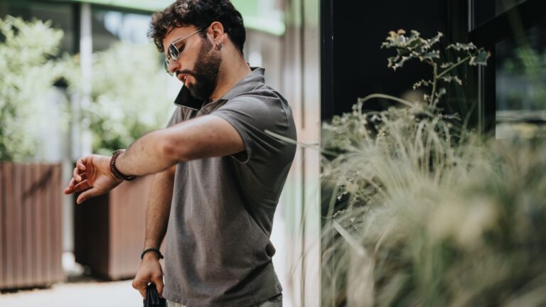 A photo of a Traveler standing outside closed restaurant during daytime, checking watch.