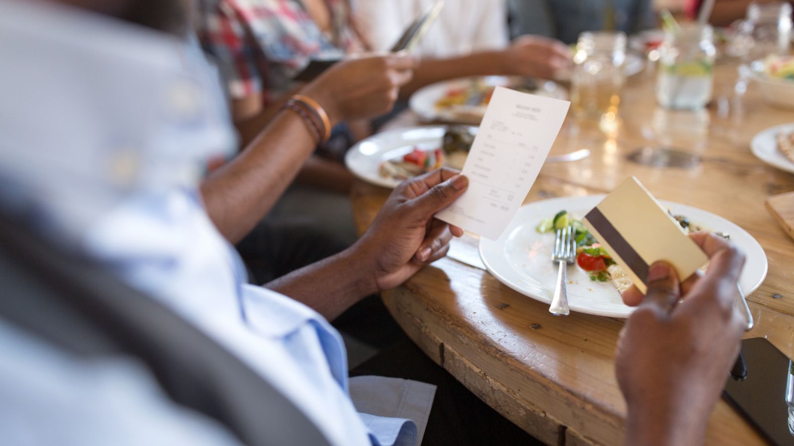 A photo of a Traveler at a restaurant abroad hesitating with cash or receipt.
