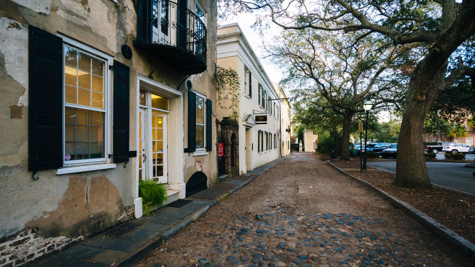 A photo of a Quiet Charleston side street at golden hour, narrow alley with historic buildings.