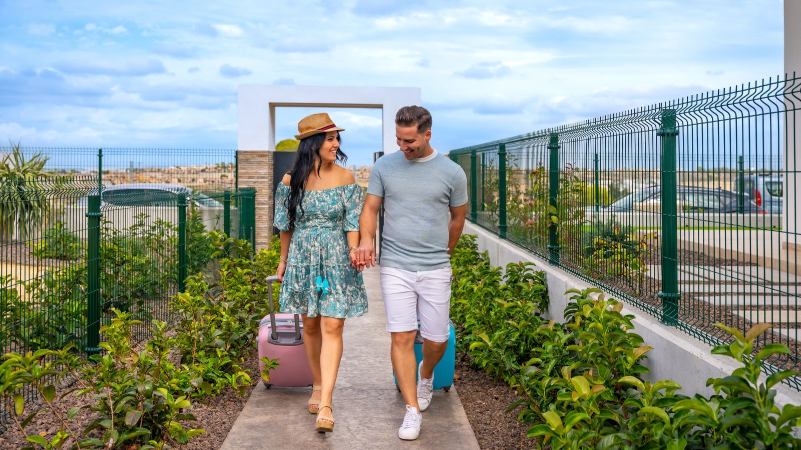 A photo of a couple Couple arriving at a Cabo resort with light luggage.