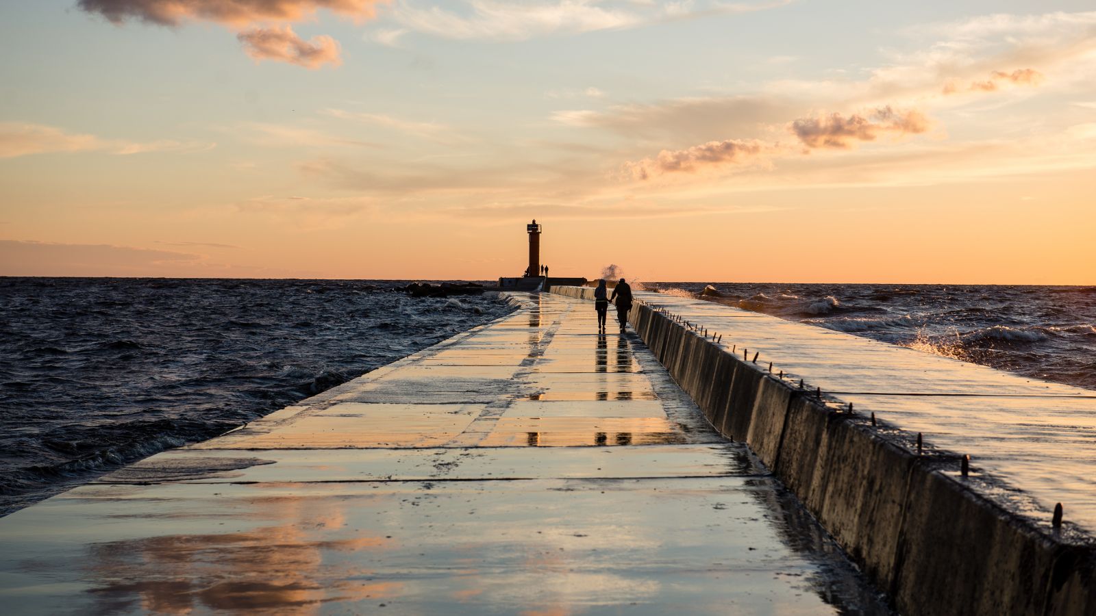 A photo of the Couple walking hand in hand along a quiet Door County shoreline.