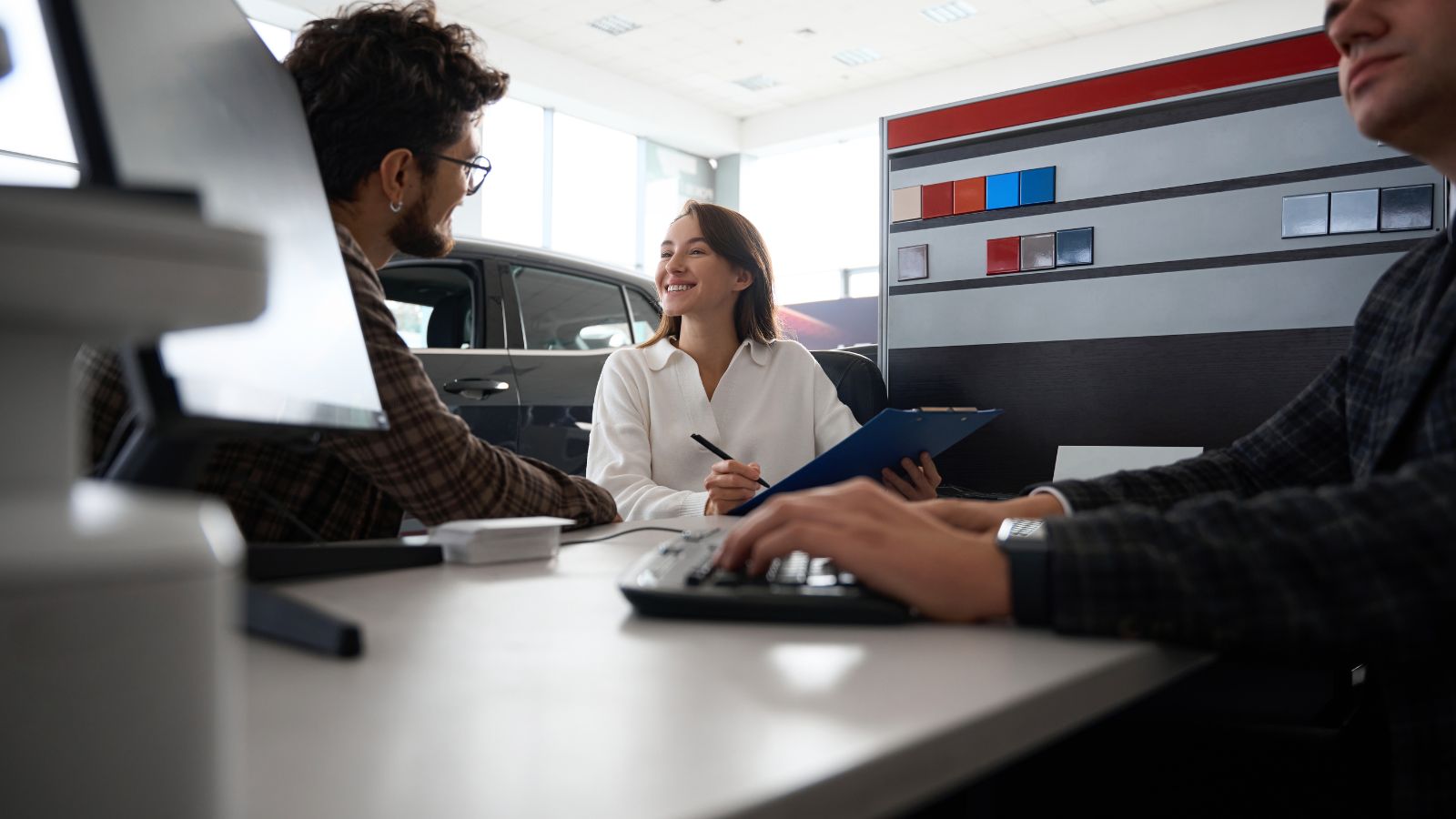 A photo of couple in a rental car counter looking happy.