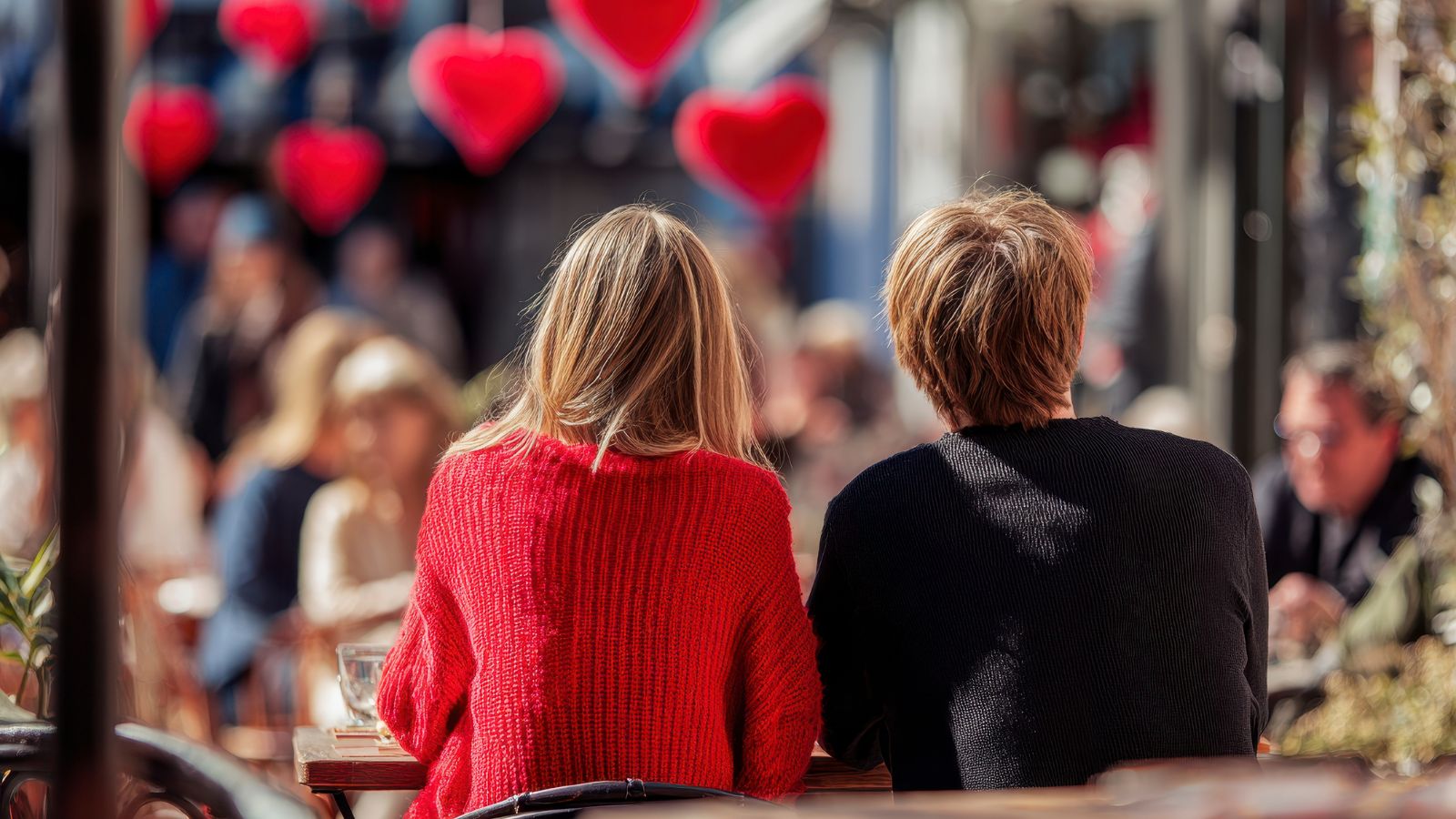 A photo of Couple sharing a quiet moment together in a busy Valentine’s setting, sitting close at a café.