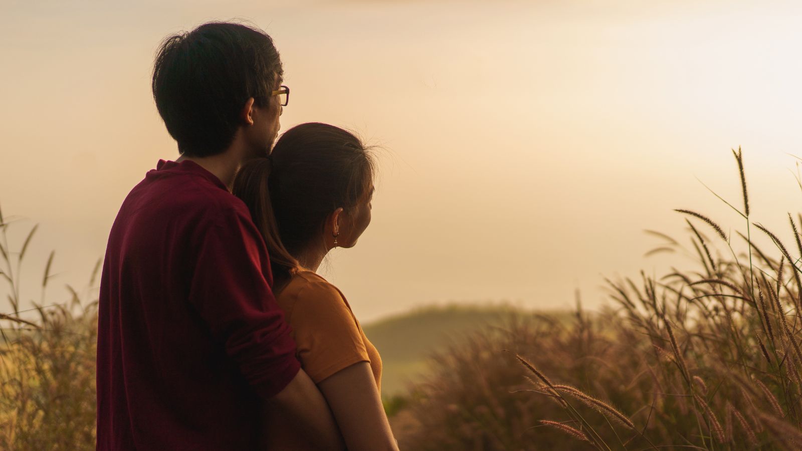 A photo of a Couple watching sunset together from a peaceful overlook, sitting close in silence.