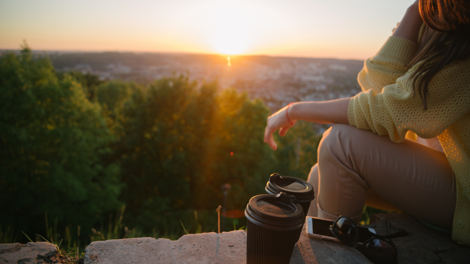 A photo of a Person sitting peacefully at a scenic overlook during golden hour.