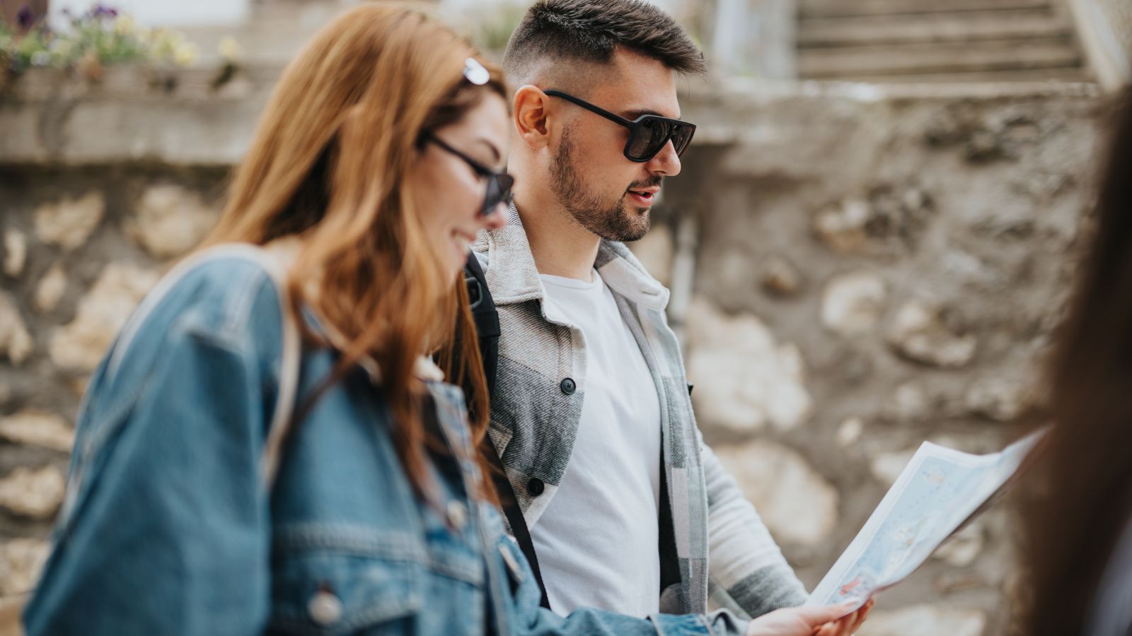 A photo of Couple exploring an unfamiliar place together, checking a map or looking around thoughtfully.
