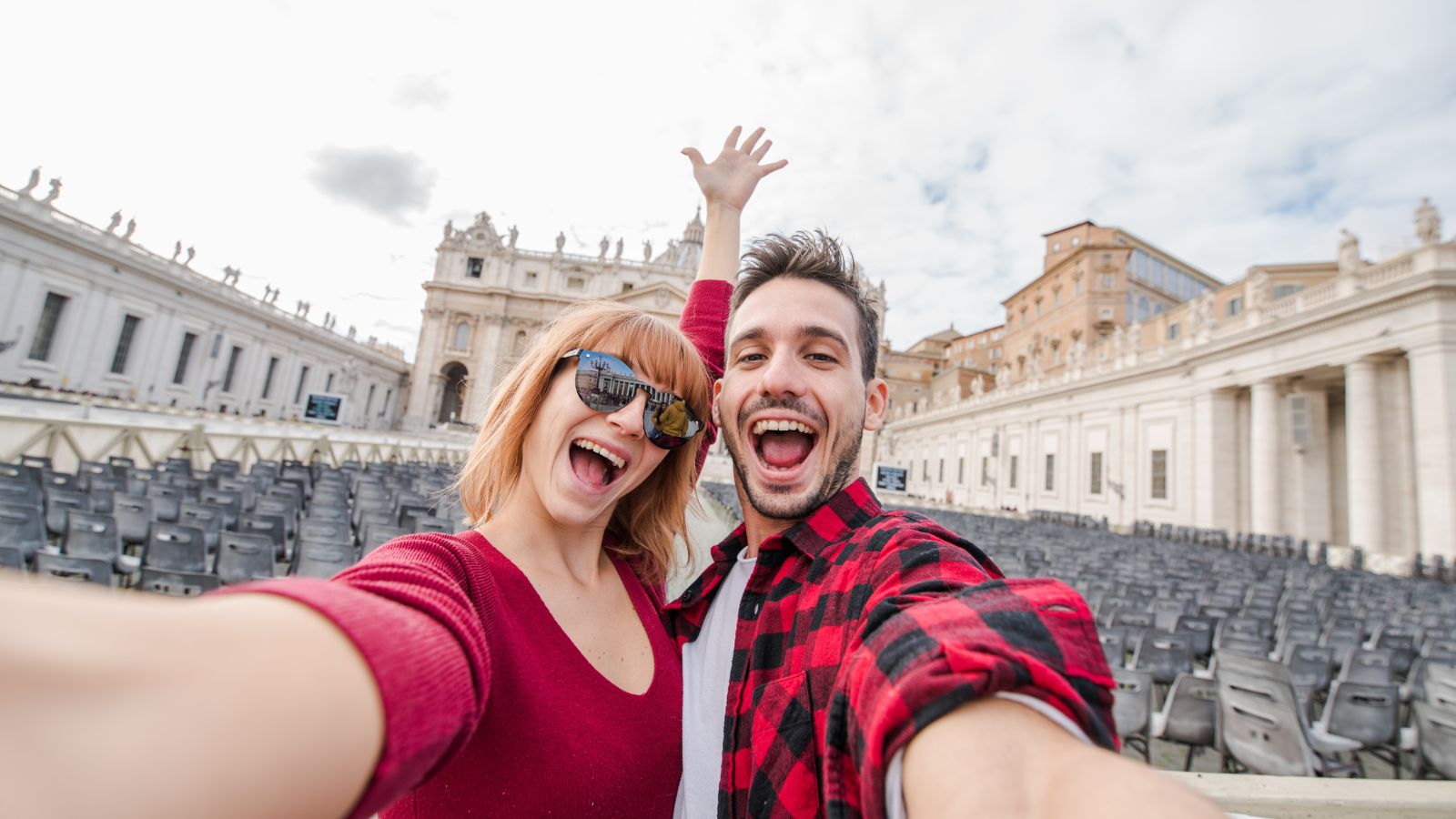 A photo of a Couple at a busy tourist landmark taking selfies.