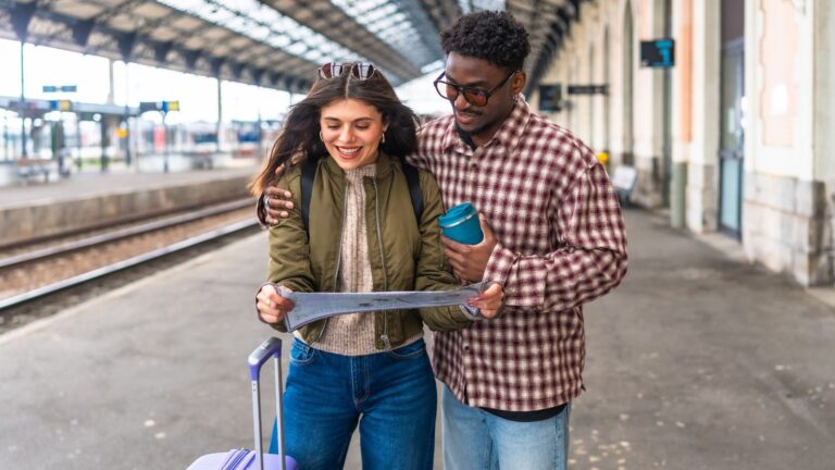 A photo of a Couple standing in a busy train station looking at a map together.