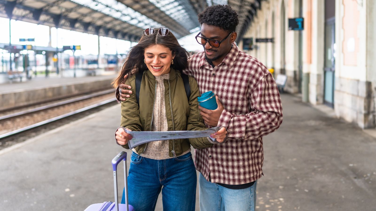 A photo of a Couple standing in a busy train station looking at a map together.