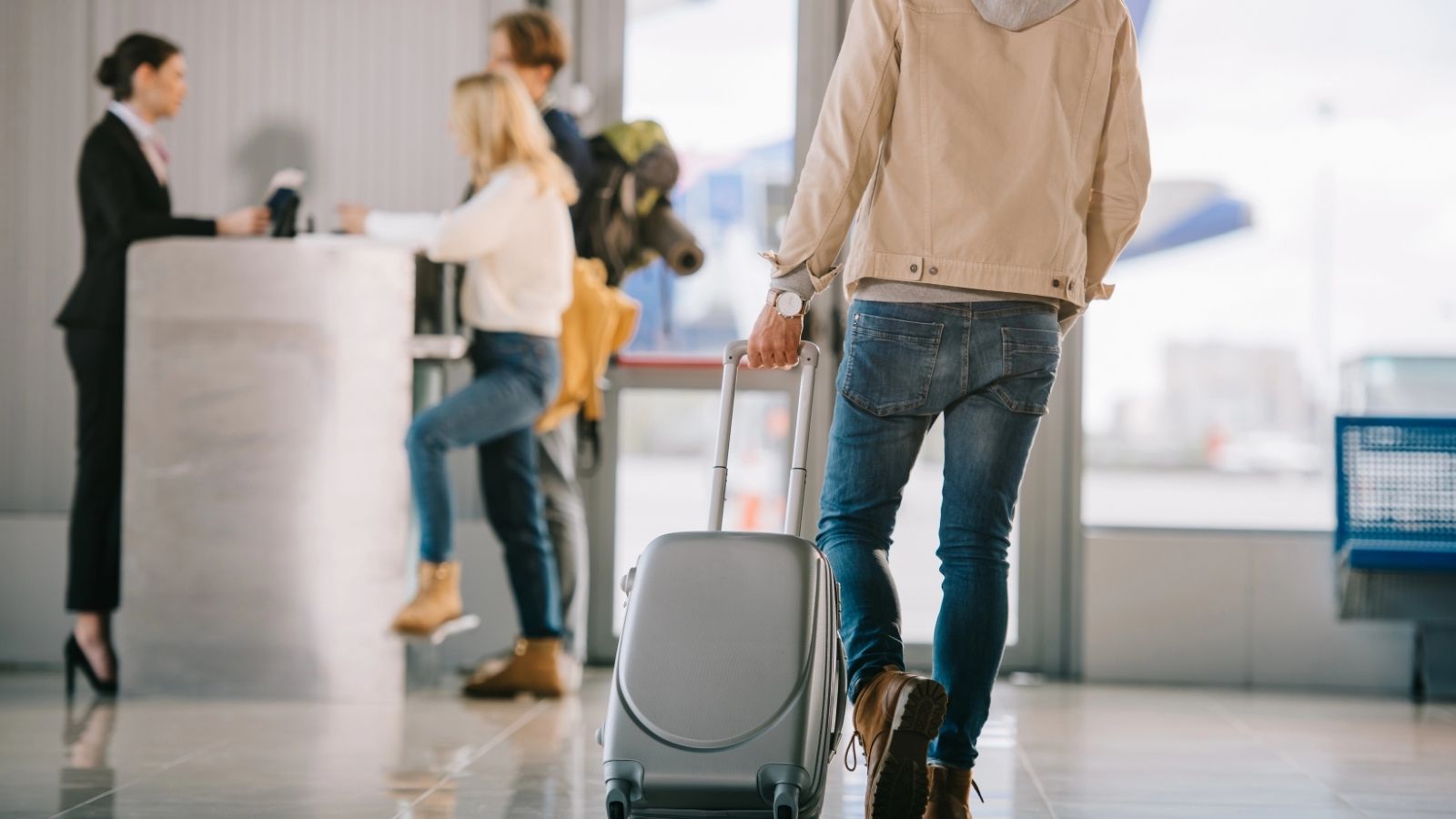 A man pulling his carry-on luggage inside the airport.