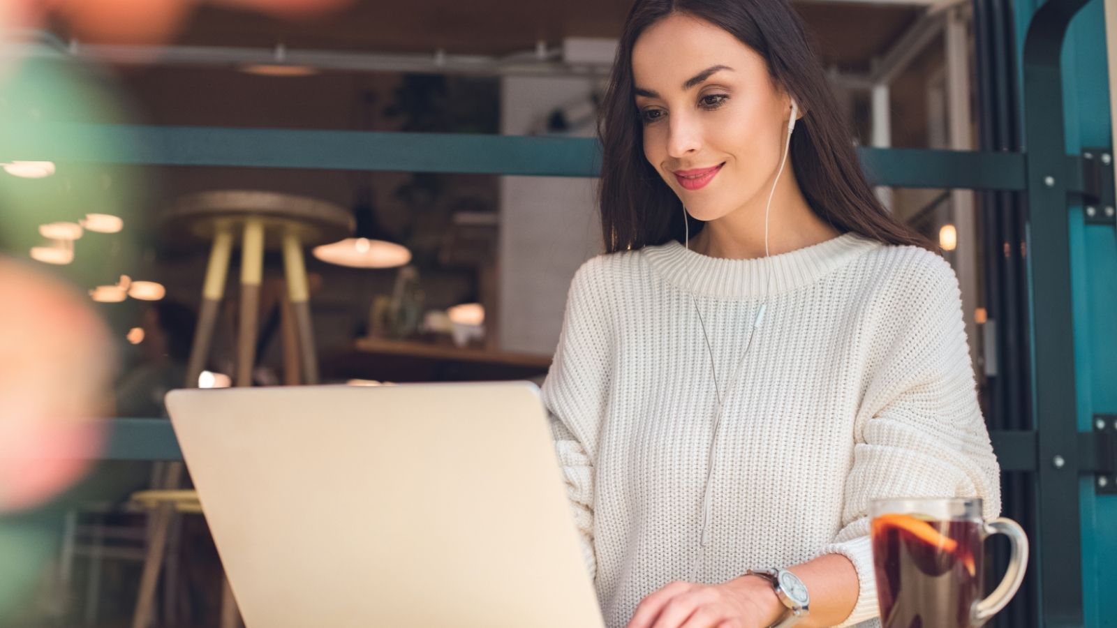 A girl working on a laptop at a coffee shop.