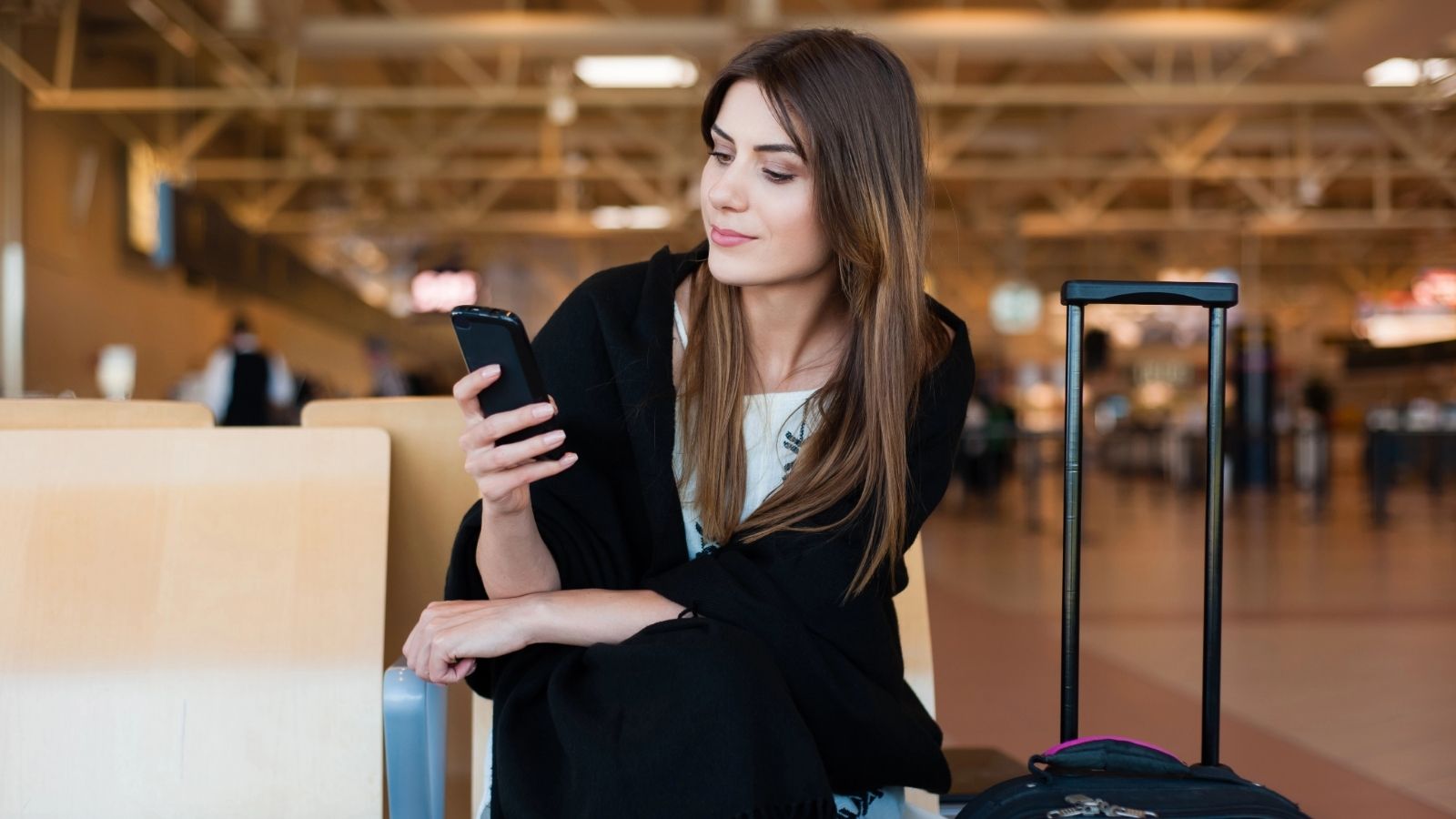 A girl on her phone at the waiting area inside the airport.