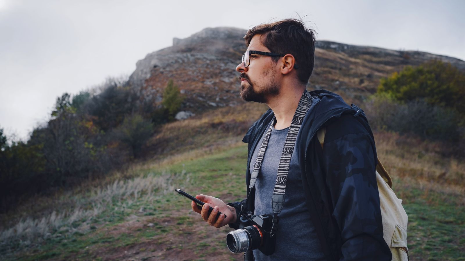 A photo of a Traveler lowering their phone while standing at a vast canyon overlook.