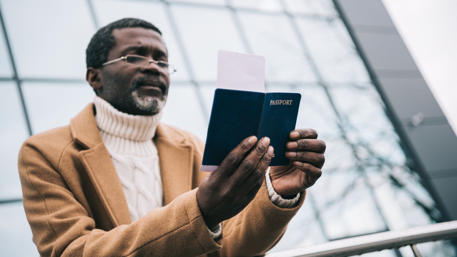 A photo of a man outside airport, close up looking at his passport.