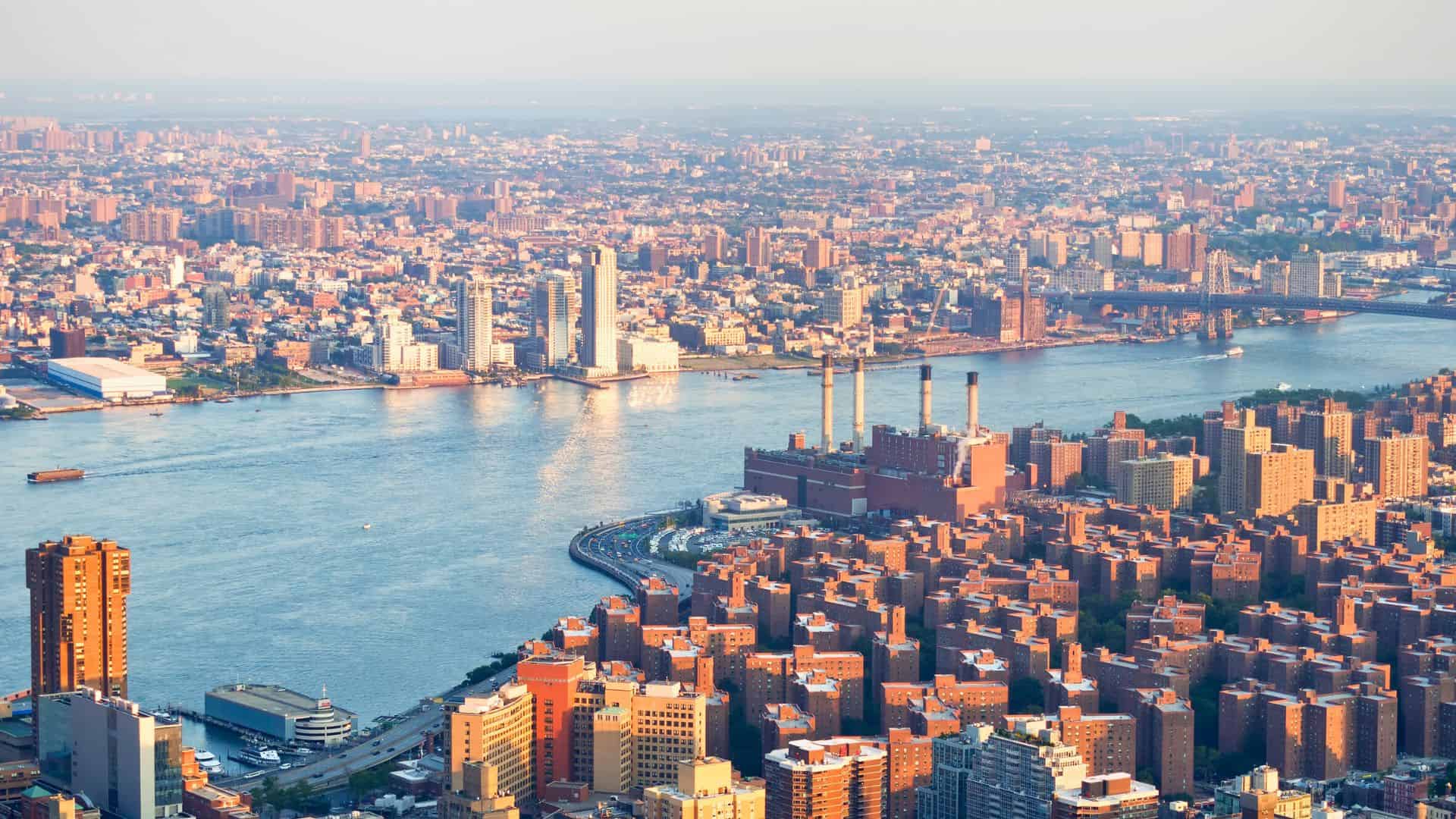 Aerial view of New York City buildings along the river on a clear, sunny day.