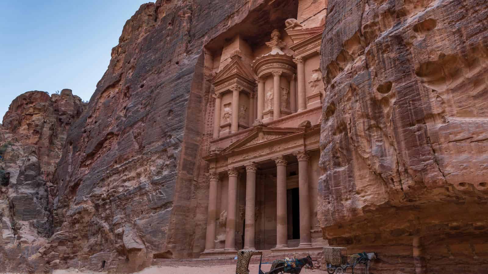 Al-Khazneh, The Treasury in Petra, Jordan, features an ancient rock-carved facade framed by towering sandstone cliffs.