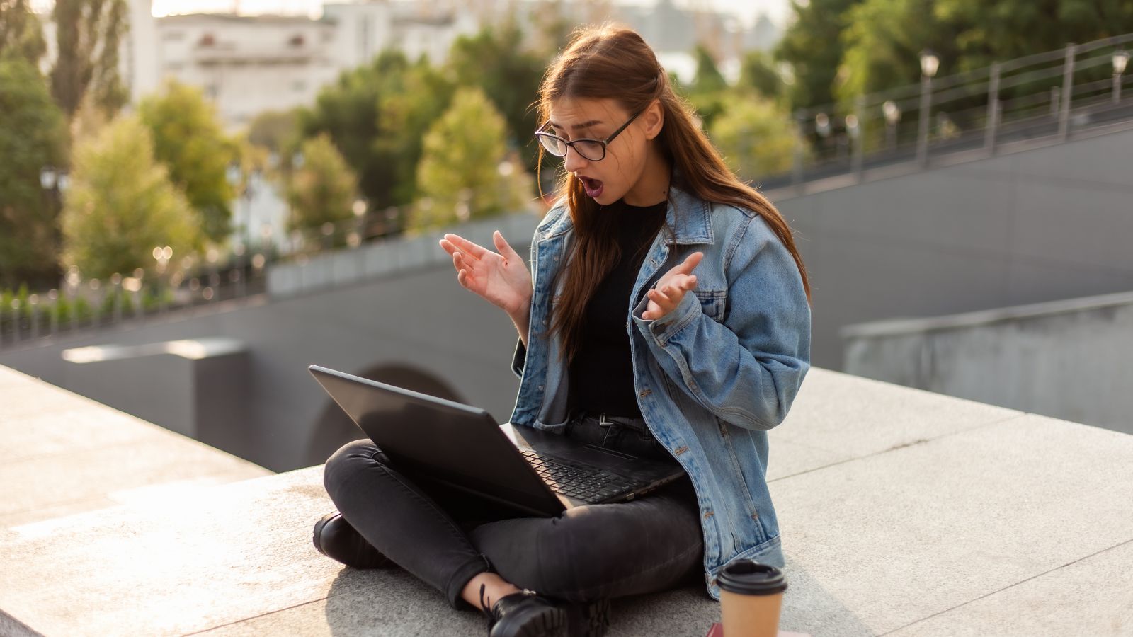A photo of a woman showing shock expression while looking at her laptop.