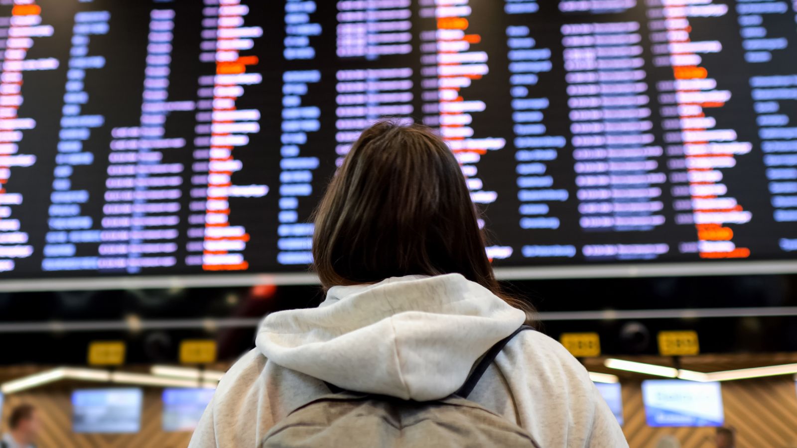 A photo of a lady passenger looking at boarding flights.
