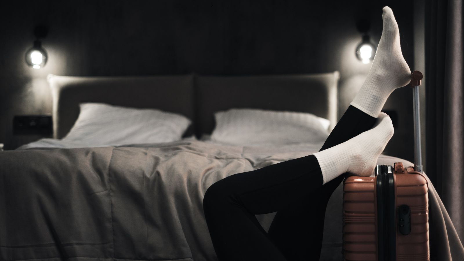 A photo of a Calm, comfortable hotel room at night, soft lighting, suitcase neatly packed, traveler resting peacefully.