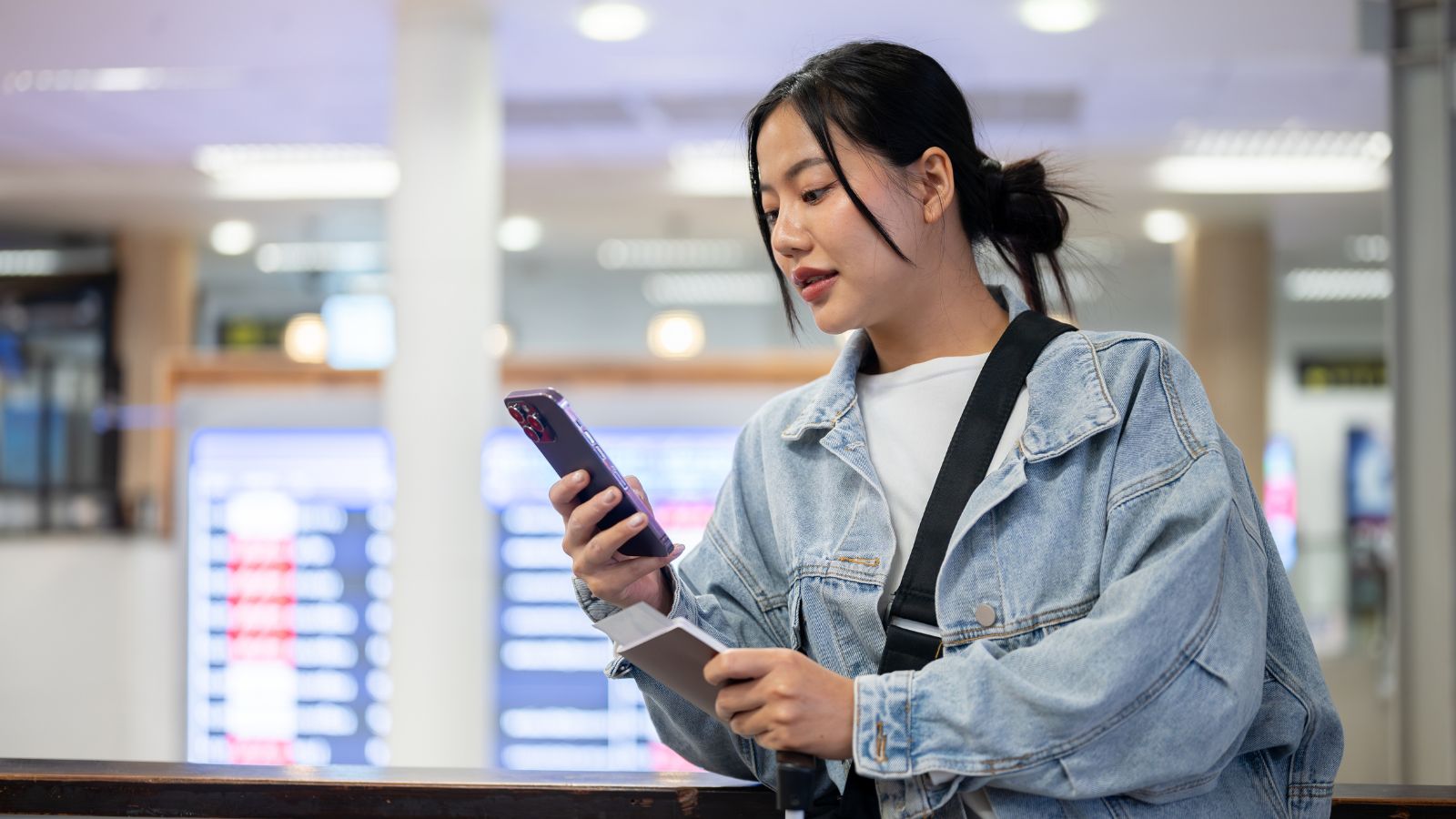 A photo of a woman checking something in her phone at the airport.
