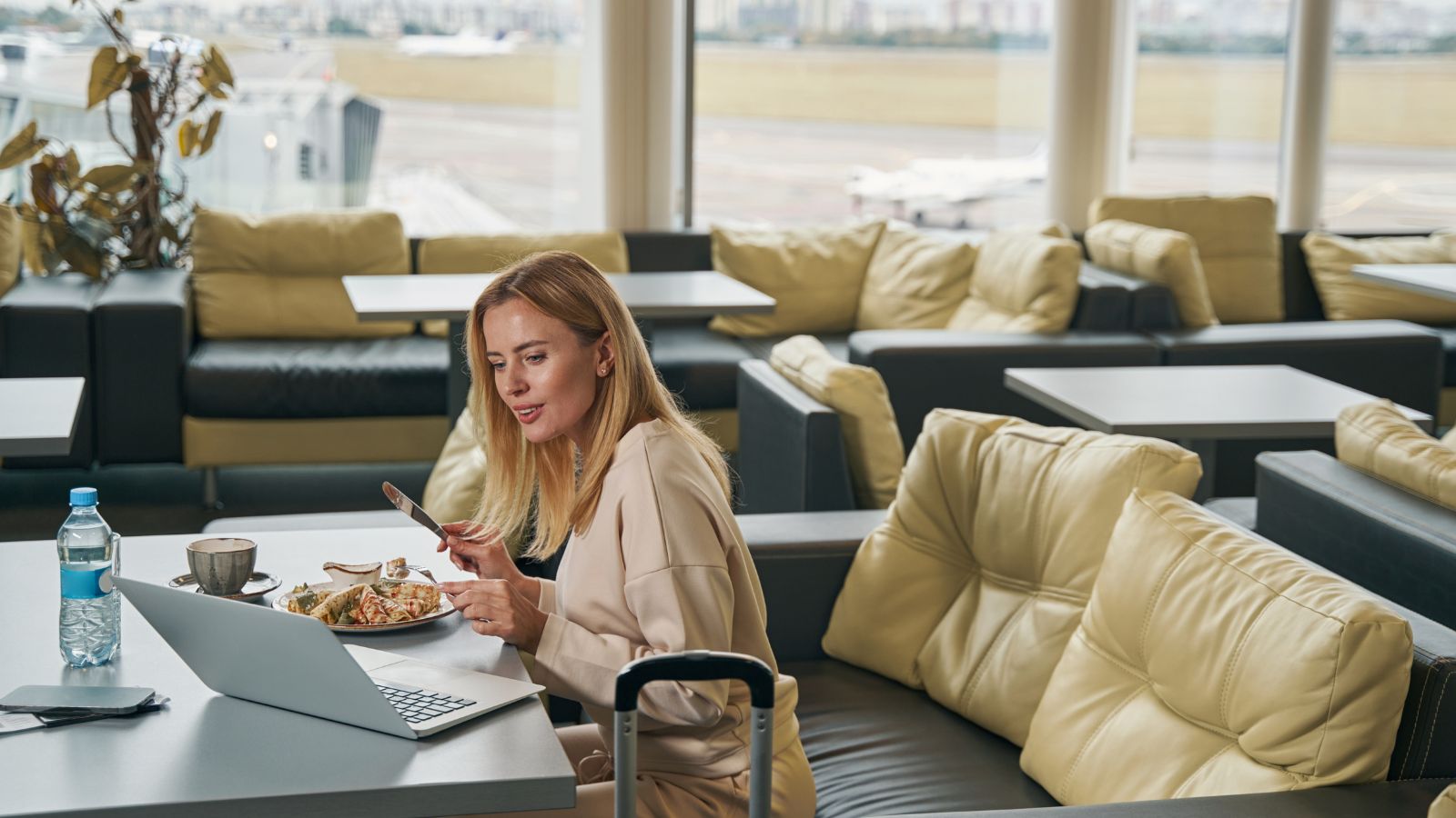 A photo of a Traveler comparing two flight options on a laptop at an airport café.