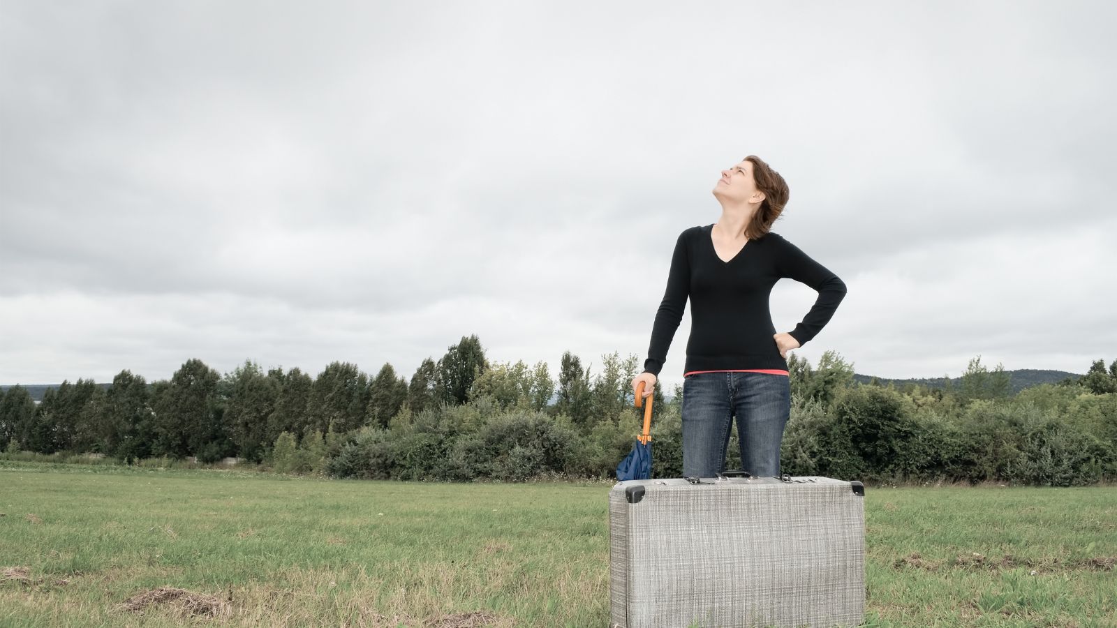 A photo of a Traveler standing under gray skies in a destination that looks less impressive than expected.