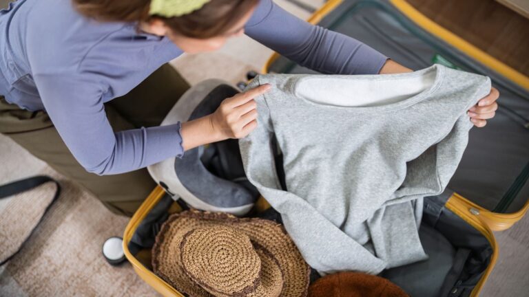 A photo of a woman packing clothes.