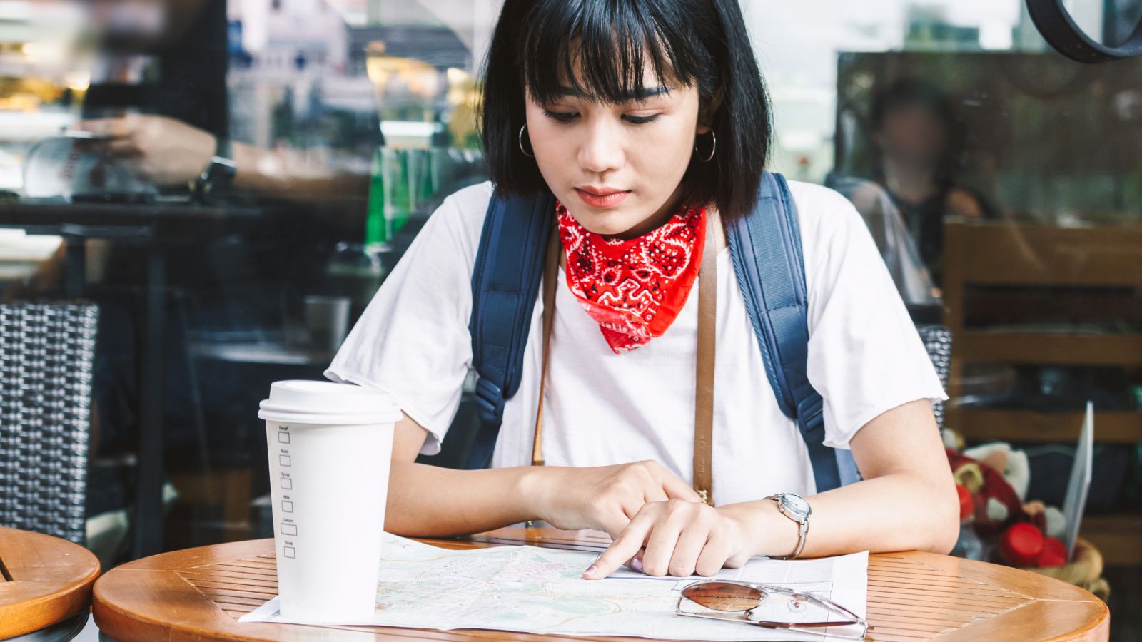 A photo of a Person sitting at a small café reviewing a map thoughtfully.