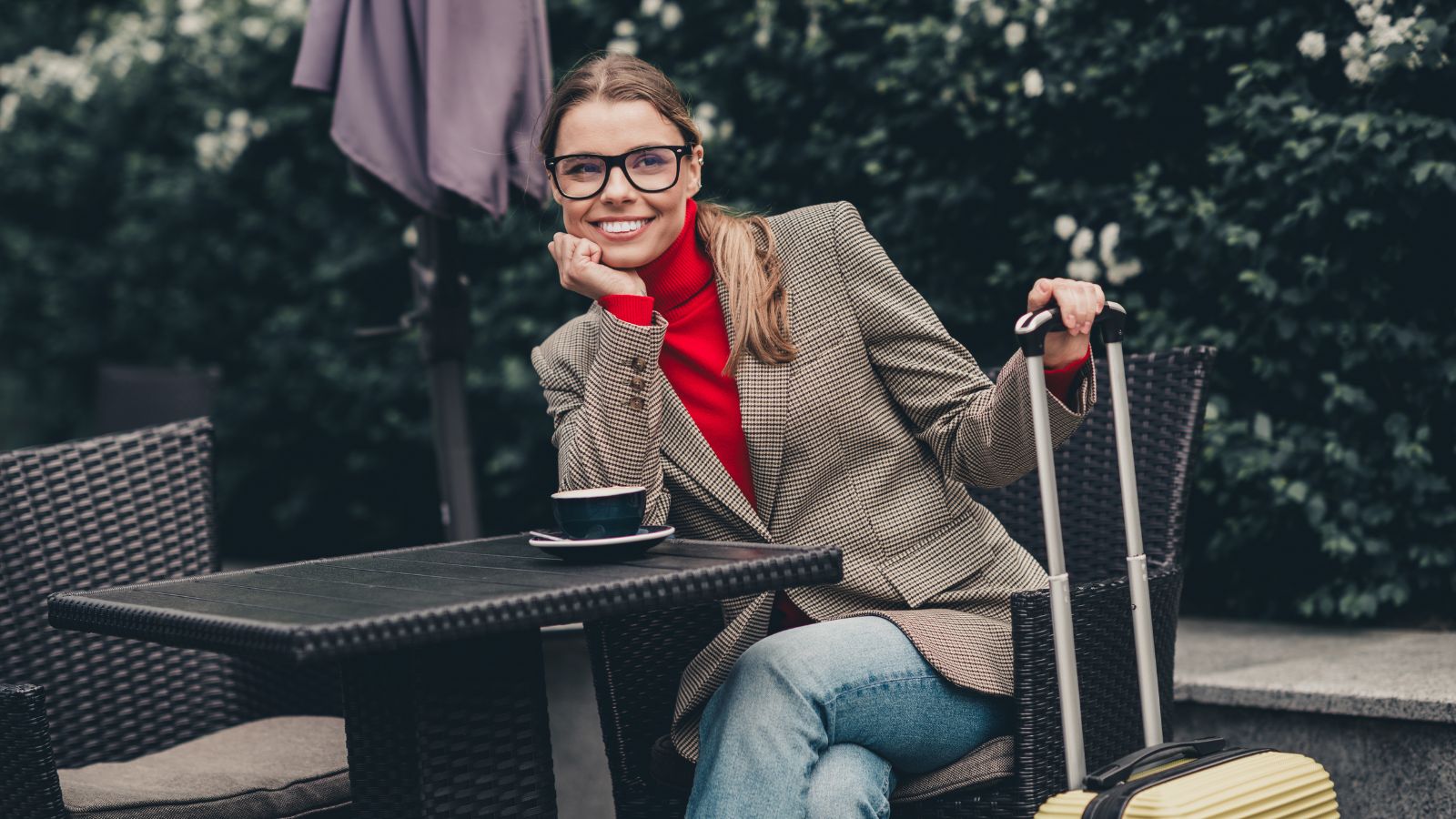 A photo of a Traveler sitting at a café with luggage beside her.