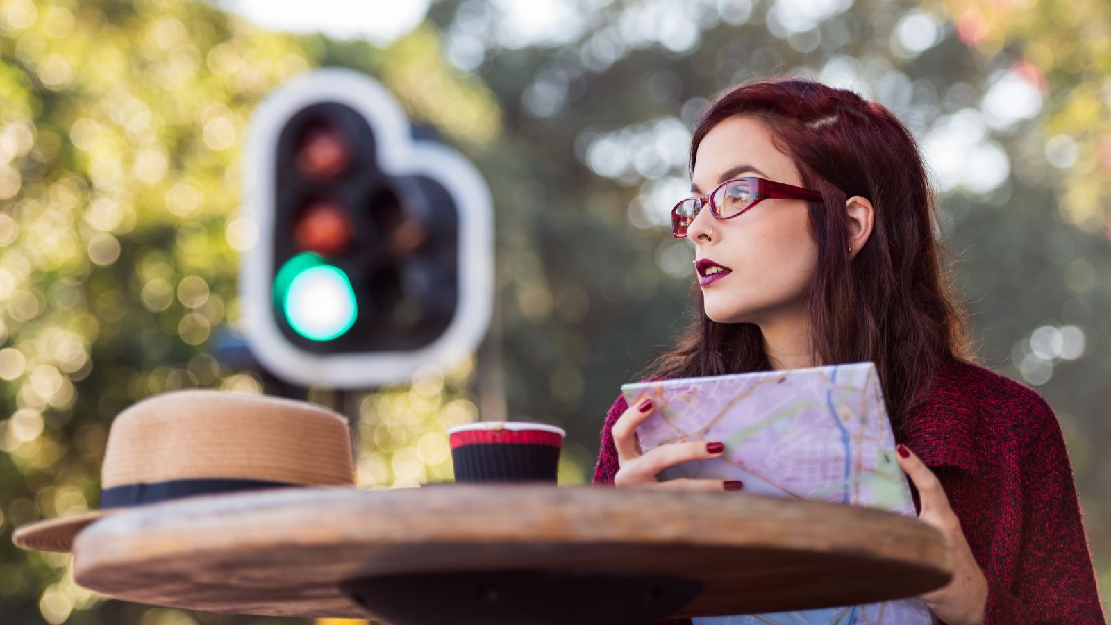 A photo of a Traveler sitting at a café table with a city map and coffee.