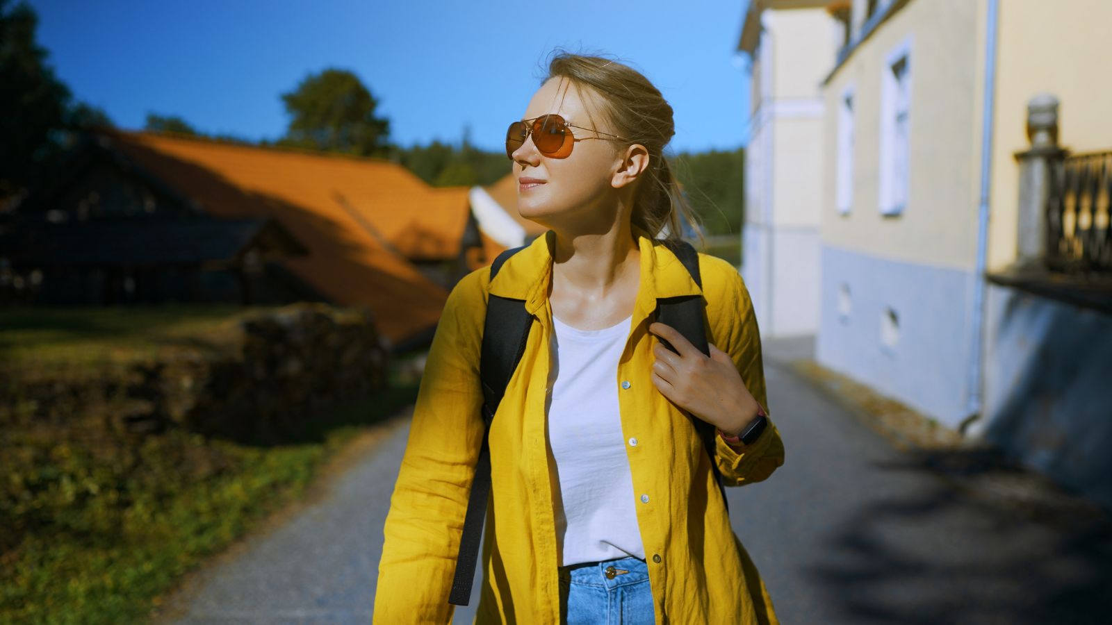 A photo of a woman Traveler slowly walking through a quiet neighborhood street.