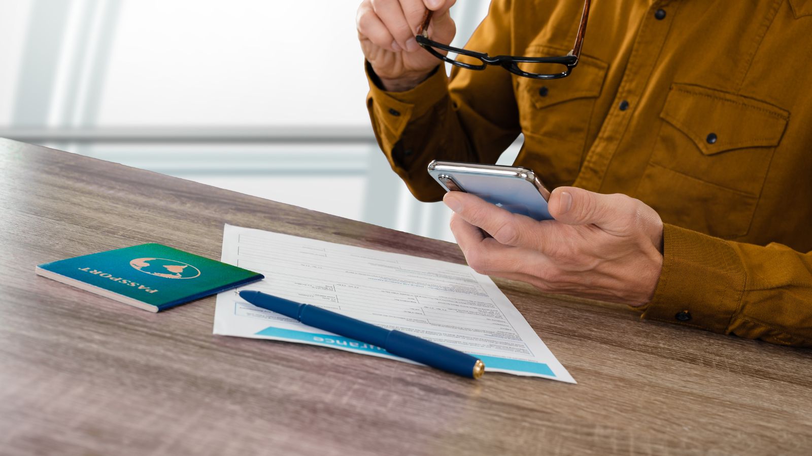 A photo of a man with a glasses looking at his phone.