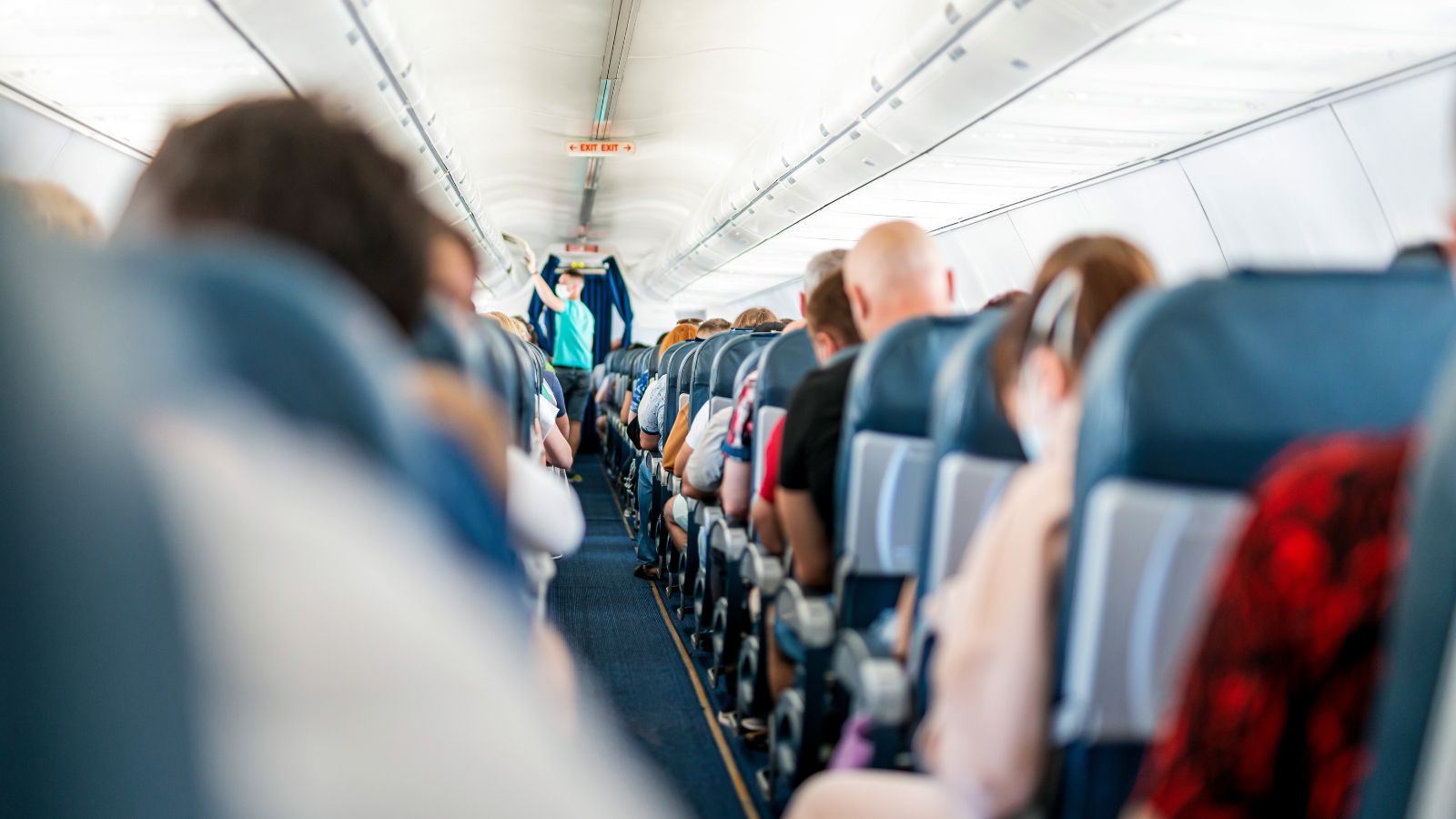 A photo of a long boarding line narrow airplane aisle.