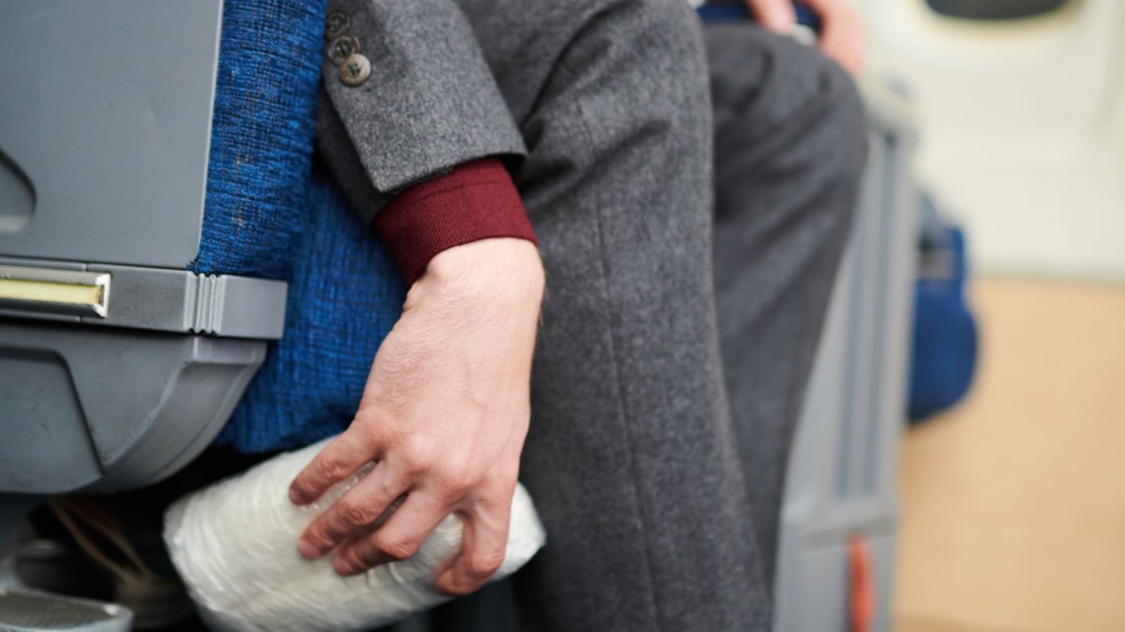 A photo of passenger retrieving essentials under airplane seat.