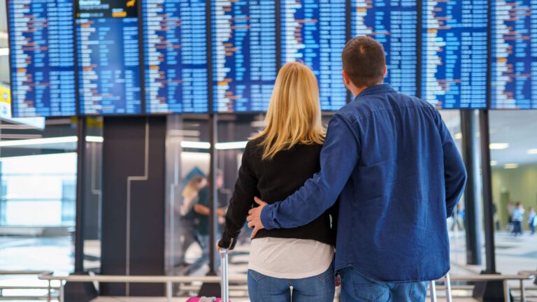 A back photo of couple together at the airport.