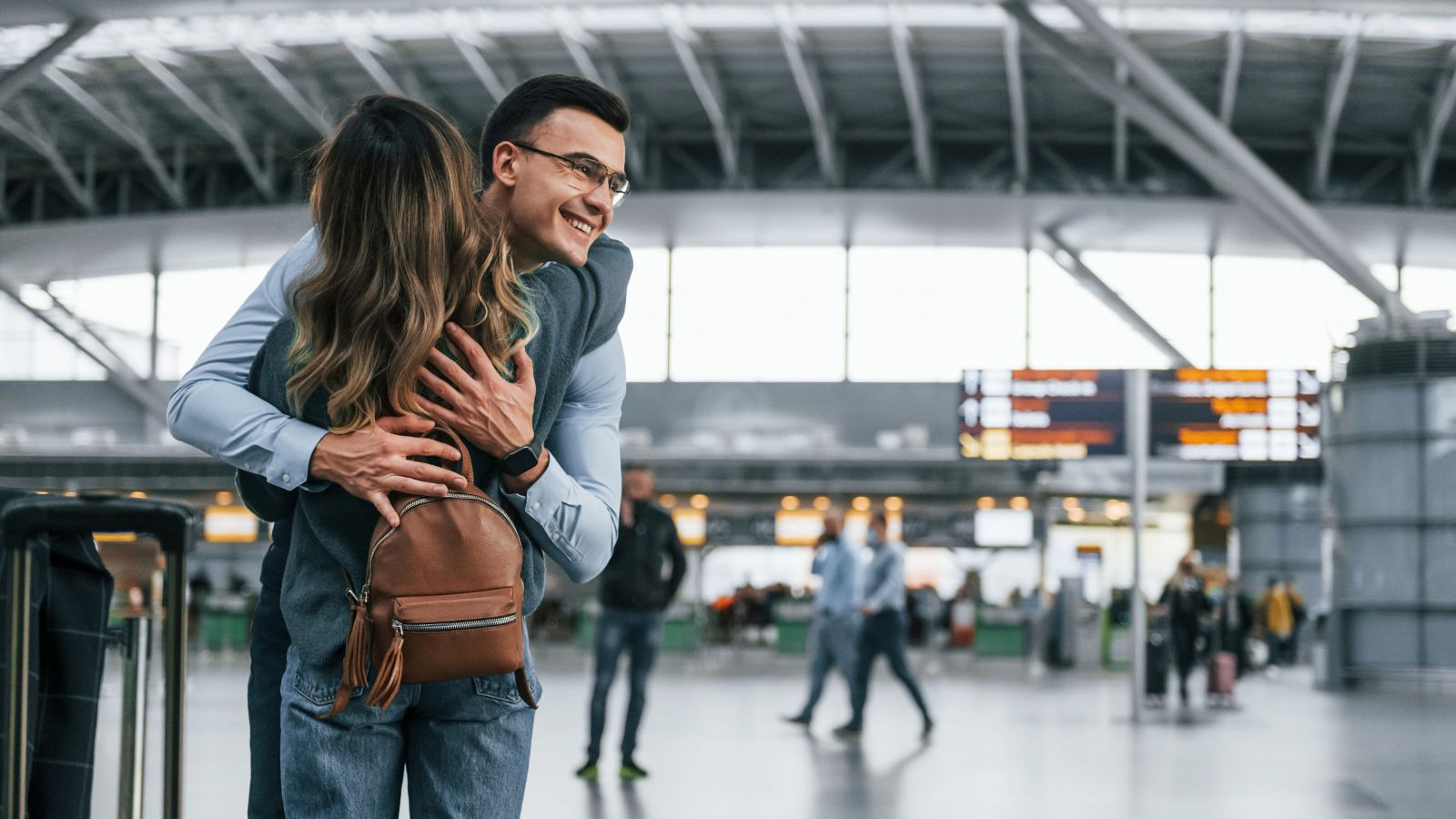 A photo of a couple embracing each other at airport.
