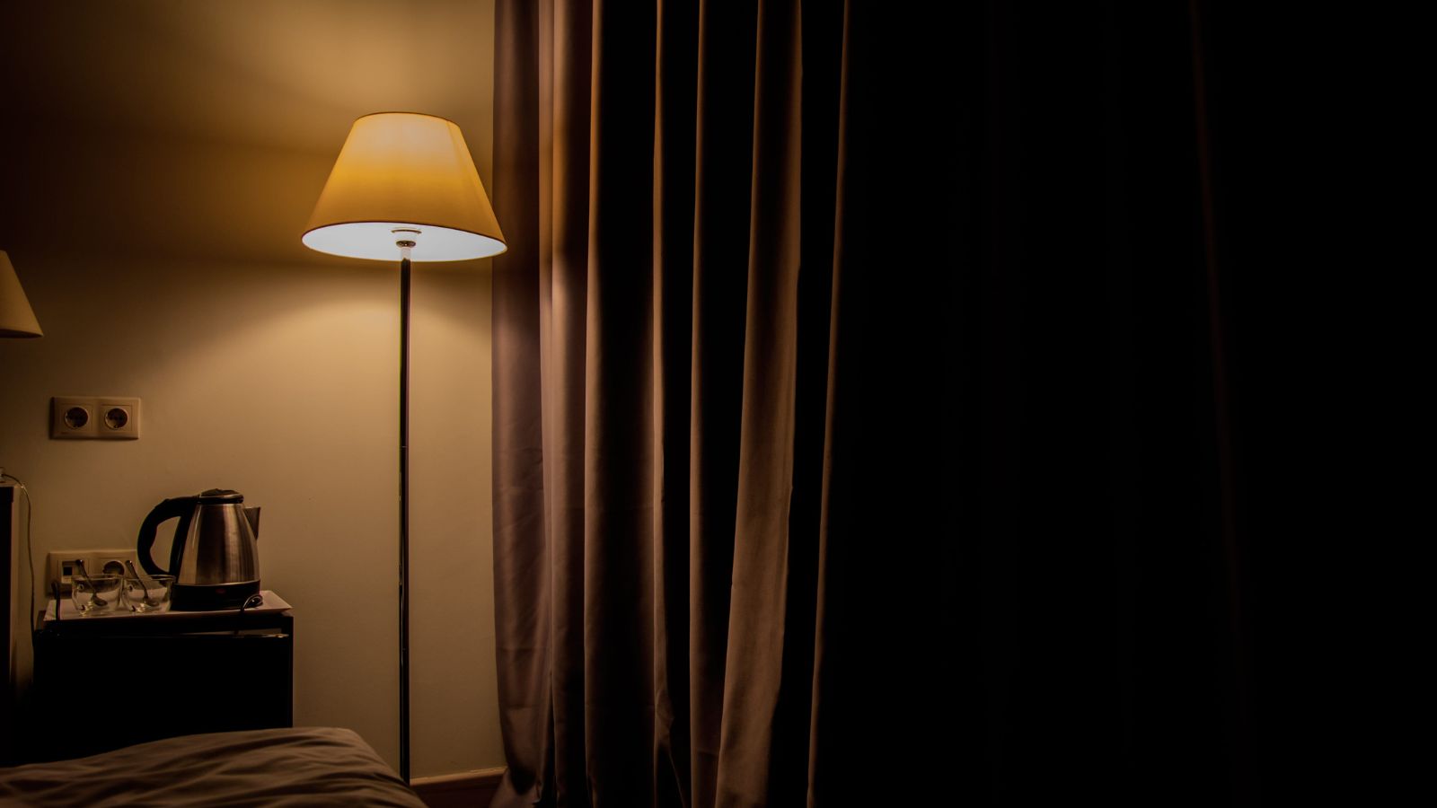 A photo of a dim hotel room entry closed curtains.