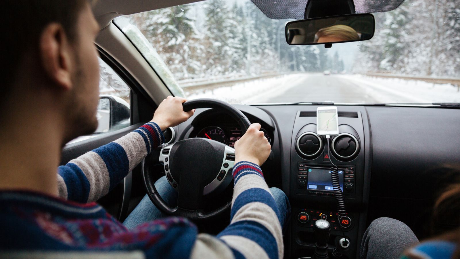 A couple of Couple driving a rental car through a winter destination.