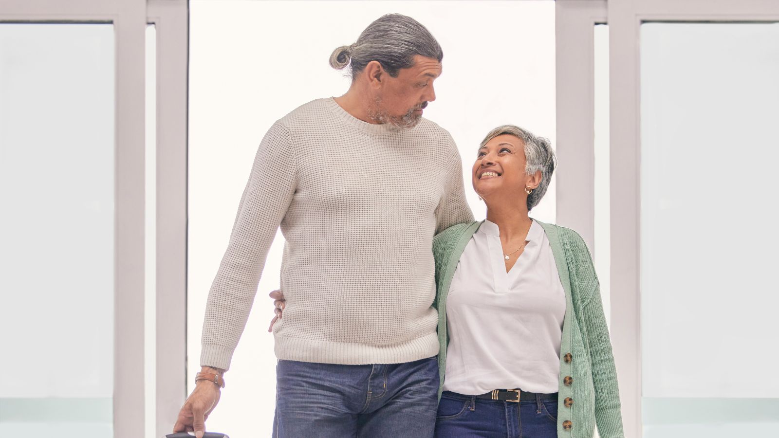 A photo of mature couple walking calmly inside airport terminal together.
