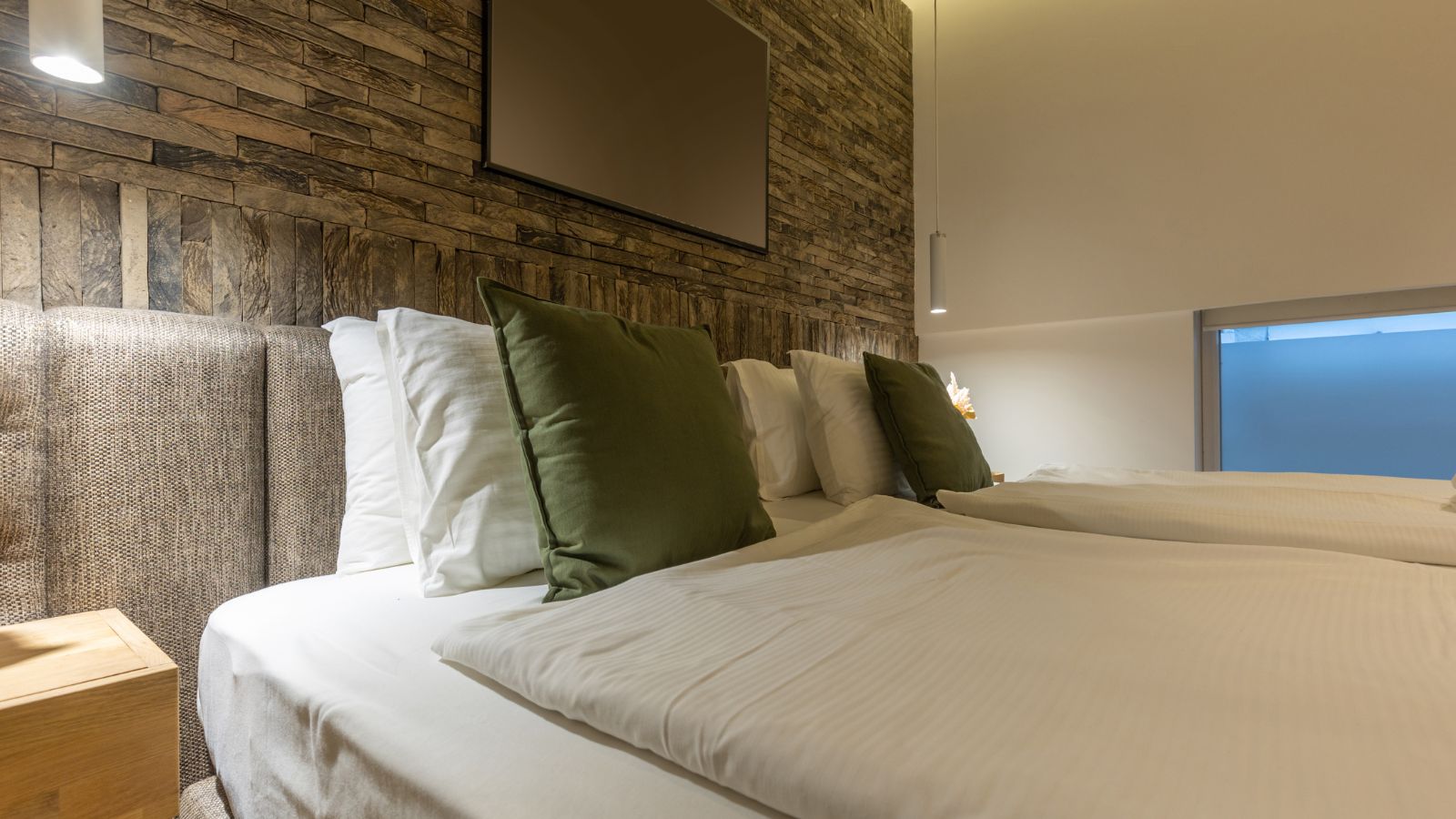 A photo of a hotel bed beside thin shared wall.