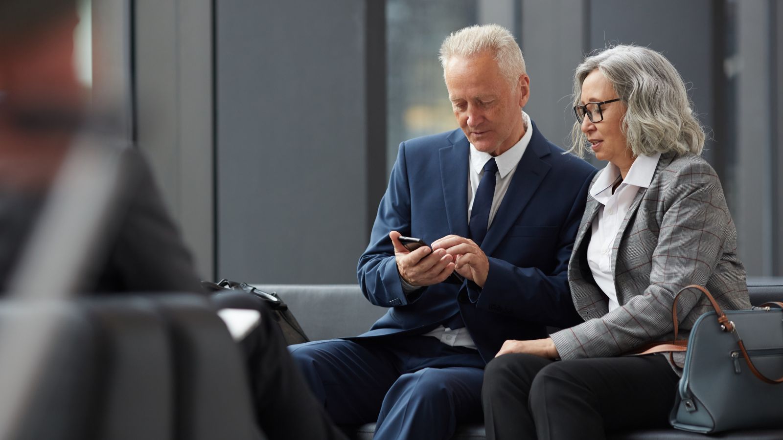 A picture that shows mature couple waiting relaxed at airplane boarding gate seats.
